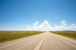 © Adam Hester - A point of view perspective of a vehicle traveling on a rural road with clouds and blue sky.