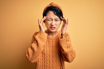 Poster - Young beautiful asian girl wearing casual sweater and diadem standing over yellow background with hand on headache because stress. Suffering migraine.