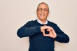 © Krakenimages.com - Senior handsome grey-haired man wearing sweater and glasses over isolated white background smiling in love doing heart symbol shape with hands. Romantic concept.