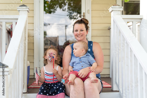 Fotomural Young mom sitting on the front porch with two toddler children on the 4th of Jul