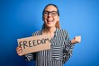 © Krakenimages.com - Young beautiful blonde woman with blue eyes holding banner with freedom message screaming proud and celebrating victory and success very excited, cheering emotion