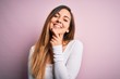 © Krakenimages.com - Young beautiful blonde woman with blue eyes wearing white t-shirt over pink background looking confident at the camera smiling with crossed arms and hand raised on chin. Thinking positive.