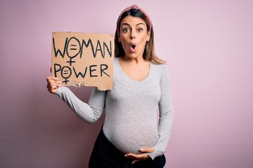 Wall Mural - Young brunette woman pregnant expecting baby holding banner asking for women power scared in shock with a surprise face, afraid and excited with fear expression