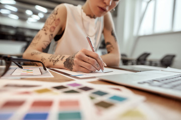 Creating a mobile app design. Young and beautiful creative female designer making a sketch while sitting at her workplace in the office