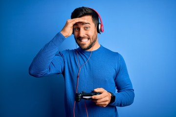 Sticker - Young handsome gamer man with beard playing video game using joystick and headphones stressed with hand on head, shocked with shame and surprise face, angry and frustrated. Fear and upset for mistake.