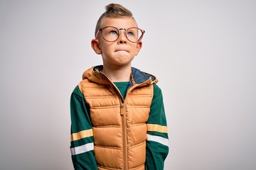 Young little caucasian kid with blue eyes wearing winter coat and smart glasses smiling looking to the side and staring away thinking.