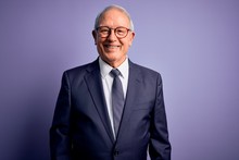Grey Haired Senior Business Man Wearing Glasses And Elegant Suit And Tie Over Purple Background With A Happy And Cool Smile On Face. Lucky Person.