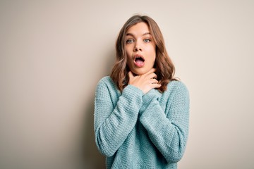 Young blonde girl wearing casual blue winter sweater over isolated background shouting and suffocate because painful strangle. Health problem. Asphyxiate and suicide concept.