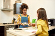 © Svitlana - Caring athmosphere. African american woman baby sitter made lunch for caucasian cute little girl. Children education, leisure activities, babysitting concept