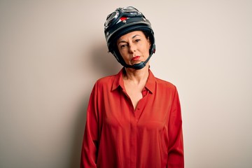 Sticker - Middle age motorcyclist woman wearing motorcycle helmet over isolated white background Relaxed with serious expression on face. Simple and natural looking at the camera.