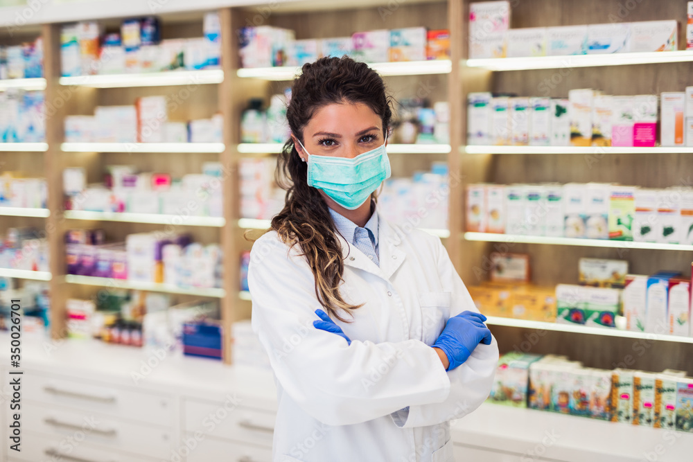 Female pharmacist with protective mask on her face working at pharmacy. Medical healthcare concept. - obrazy, fototapety, plakaty 