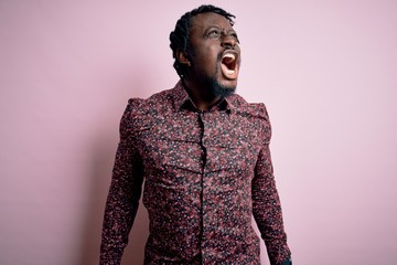 Canvas Print - Young handsome african american man wearing casual shirt standing over pink background angry and mad screaming frustrated and furious, shouting with anger. Rage and aggressive concept.