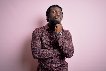 Poster - Young handsome african american man wearing casual shirt standing over pink background with hand on chin thinking about question, pensive expression. Smiling with thoughtful face. Doubt concept.