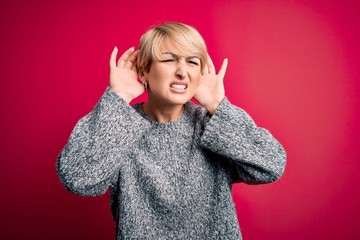 Sticker - Young blonde woman with modern short hair wearing casual sweater over pink background Trying to hear both hands on ear gesture, curious for gossip. Hearing problem, deaf