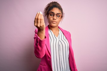 Poster - Beautiful african american businesswoman wearing jacket and glasses over pink background Doing Italian gesture with hand and fingers confident expression