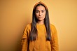 © Krakenimages.com - Young beautiful asian woman wearing casual sweater and diadem over yellow background with serious expression on face. Simple and natural looking at the camera.