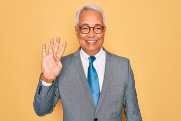 Poster - Middle age senior grey-haired handsome business man wearing glasses over yellow background showing and pointing up with fingers number four while smiling confident and happy.