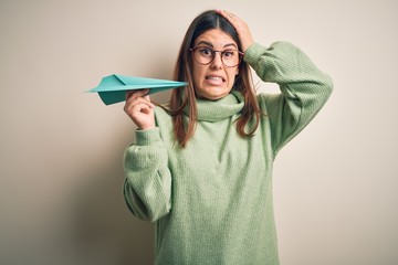 Poster - Young beautiful woman holding airplane of paper standing over isolated grey background stressed with hand on head, shocked with shame and surprise face, angry and frustrated. Fear and upset