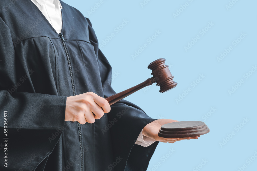 Female judge with gavel on light background, closeup