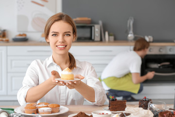 Canvas Print - Female confectioner with tasty desserts in kitchen