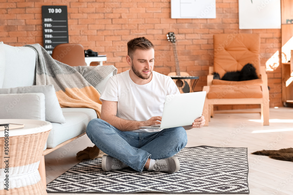 Young man with laptop working at home