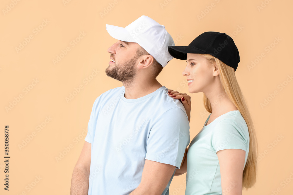 Young couple in stylish caps on color background
