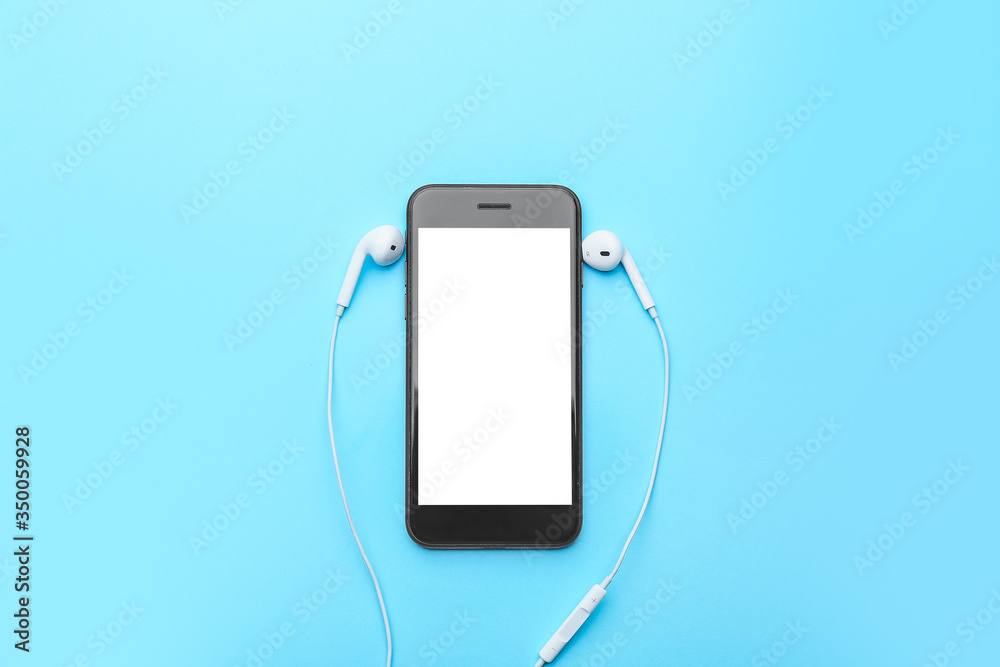 Modern mobile phone with earphones on color background