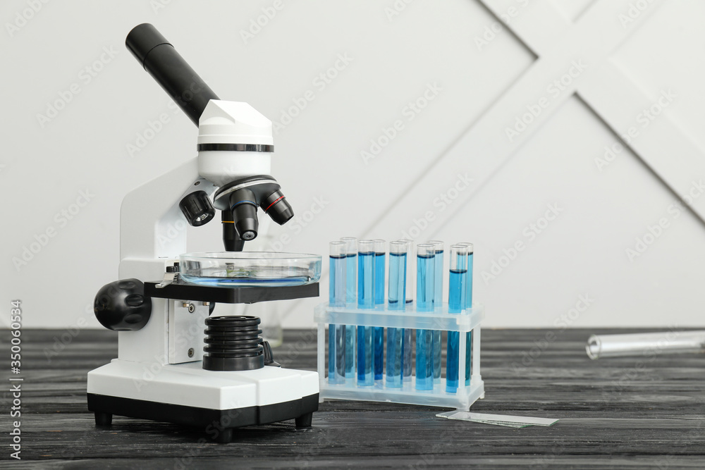 Modern microscope and test tubes on table