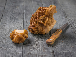 Wall Mural - A knife with a wooden handle and gyromitra mushrooms on a black wooden table.