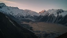 Time Lapse Of Sunlight Shining On The Peak Of Mount Cook With Clouds Rolling Over Snow Covered Mountains And Mount Cook Village In The Valley Below. Panoramic Views From Red Tarn Lookout In New Zealan