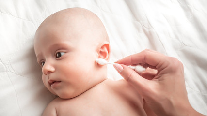 Close-up Of A Mother Cleaning Baby Ear With Swab. Concept Hygiene cleaning wipe, pure, clean