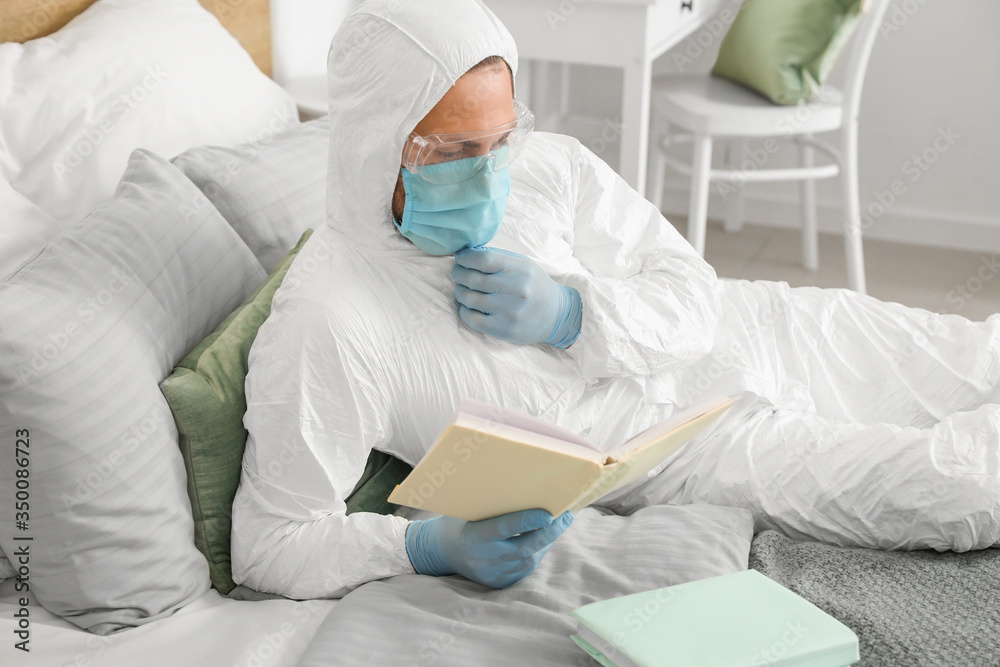 Man in biohazard suit reading book at home