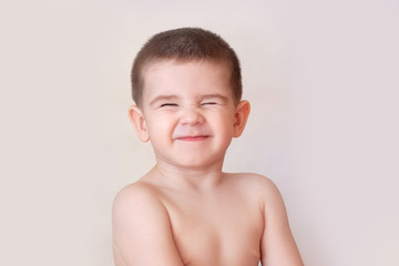 Wall Mural - happy smiling child with squeezed or closed eyes on white background