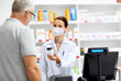 © Syda Productions - medicine, pharmaceutics and healthcare concept - apothecary wearing face protective medical mask for protection from virus disease and senior male customer buying drug at drugstore