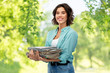 © Syda Productions - recycling, waste sorting and sustainability concept - smiling young woman holding heap of paper magazines over green natural background
