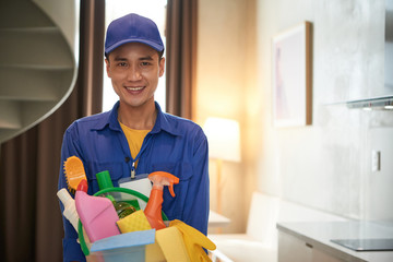 Sticker - Portrait of smiling Vietnamese cleaning service worker holding bucket of detergents and disinfectant sprays