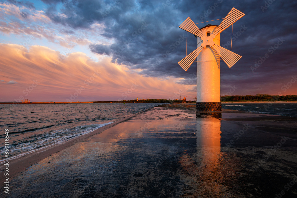 lighthouse in the shape of a windmill in Swinoujscie in Poland during the dramatic sunset - obrazy, fototapety, plakaty 