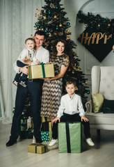 parents with two children at home under the tree with gifts