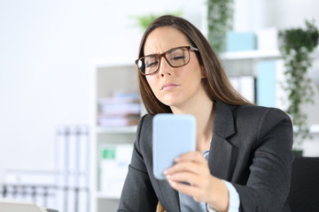 Executive with eyesight problem reading on phone at office