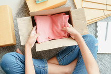 Top View Of Asian Girl Is Preparing Pink Clothes Down Inside A Parcel Box According To The Customer Order. 