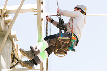 Industrial climber in helmet and overall working on height. Risky job. Professional worker