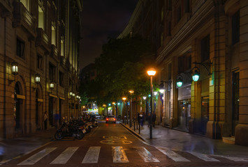 Fototapete - Cozy street with tables of bar in Barcelona, Catalonia, Spain. Architecture and landmark of Barcelona. Night cityscape of Barcelona