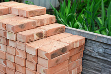 A Pile Of Red Bricks Are Neatly Piled Together On The Construction Site To Build A Brick Wall Of The House.