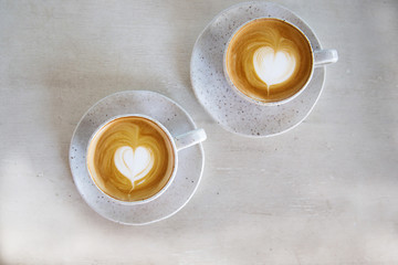 Two Cups of hot cappuccino on white wooden table background.