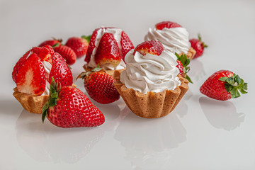 gourmet tartlets with whipped cream and fragrant juicy strawberries on a glass surface