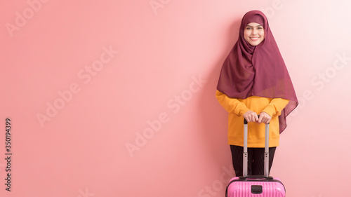 Fotografía muslim woman with hijab is holding luggage on pink background , people travel co