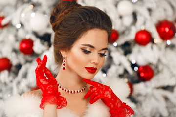 Wall Mural - Bride portrait of Elegant woman with ruby jewelry set and red gloves. Beautiful brunette lady with wedding hairstyle, beauty makeup wears posing over xmas tree background