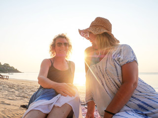 Two senior women laughing and having fun at sea shore at sunny day