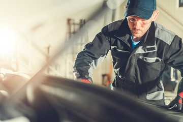 Wall Mural - Mechanic At Workshop Checking Under Hood Of Car.