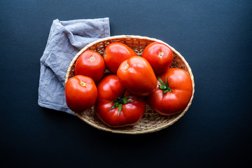 Top view of a basket of fresh tomatoes on a dark background. Healthy and natural food concept,